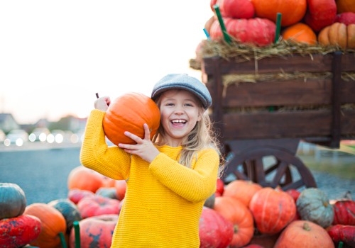 Happy little girl showing off a pumpkin from a pumpkin patch near the Quad Cities