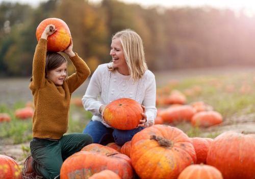 Mother and child smiling and picking pumpkins in a pumpkin patch near Moline IL