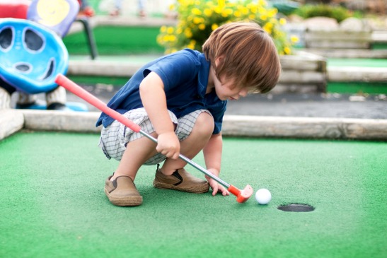 A boy looks at his ball while playing putt putt at the Apple Orchard for Springfield IL