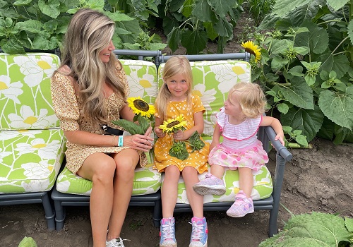 A mother and her daughters pose with sunflowers, which is one of the offerings at Tanners Orchard in addition to Apple Orchards near Kewanee IL