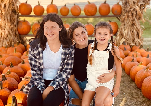 A woman and her daughters pose with pumpkins at Tanners Orchard, which offers Family Activities by Champaign IL