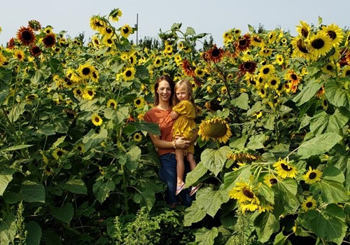 A woman and her daughter pose in front of sunflowers at Tanners Orchard, which is the Best Apple Orchard in Illinois